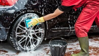A man cleaning the tire of a car.
