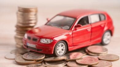 Red car model on stacked coins