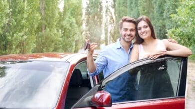 Happy couple with a brand new car, holding keys, showcasing the benefits of flexible financing for a smart car purchase.