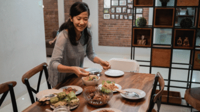 Housewife mom setting a family meal on the table at home to celebrate Mother's Day 2025.