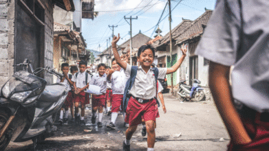 Filipino children in school uniforms happily walk on a neighborhood street, highlighting the 2025-2026 Philippine School Calendar Reversion.